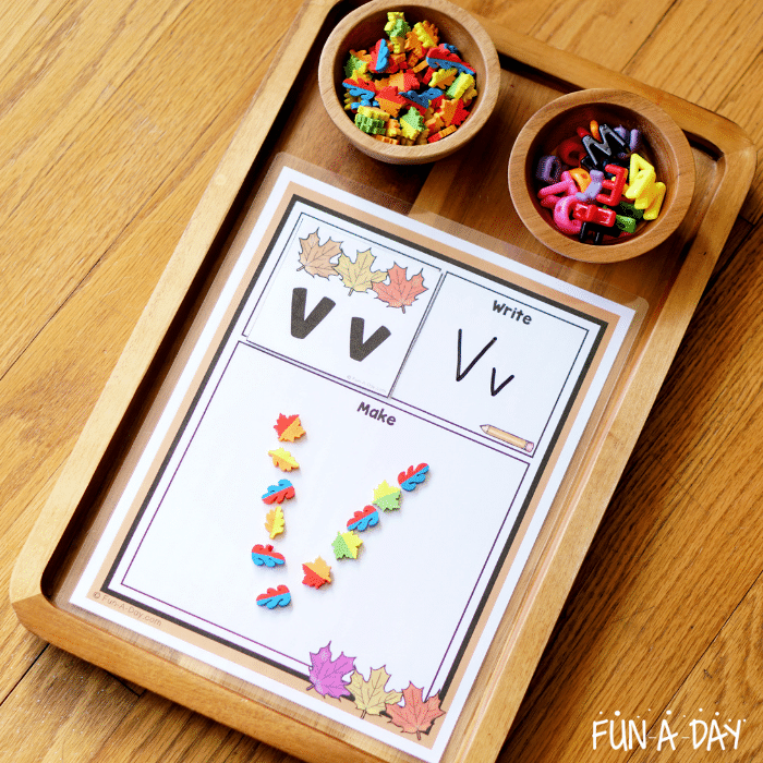 Vv fall alphabet card on mat, with leaf mini erasers making the letter v.