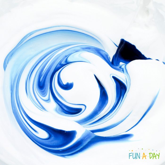 Blue food dye swirling around white slime mixture.