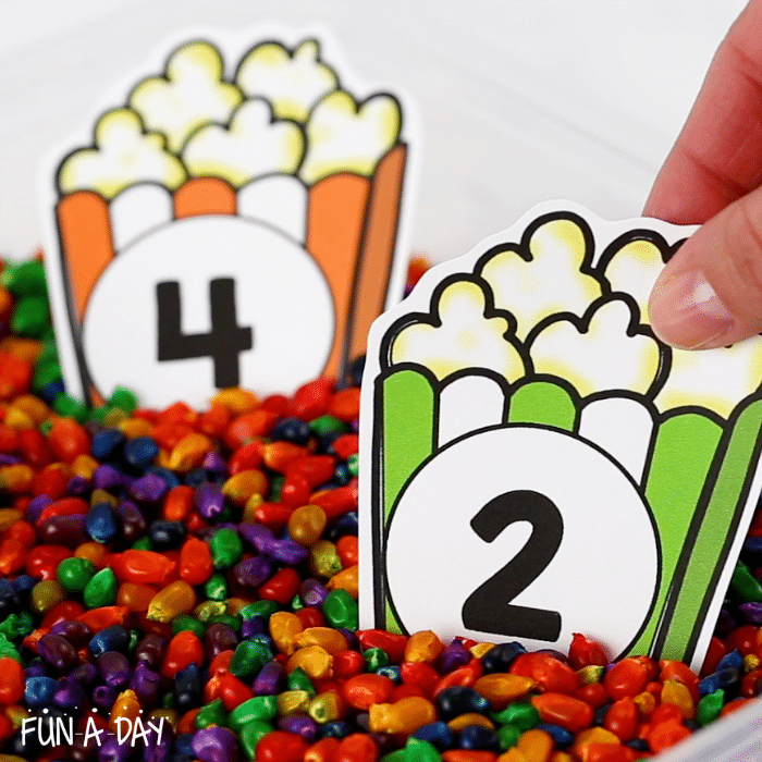 Number four and two popcorn counting printable in a bin of multi-colored corn.