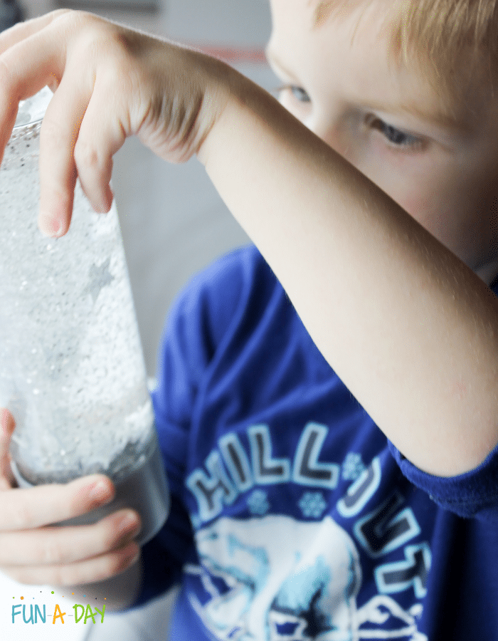 Child examining a star sensory bottle, while holding it upside down.