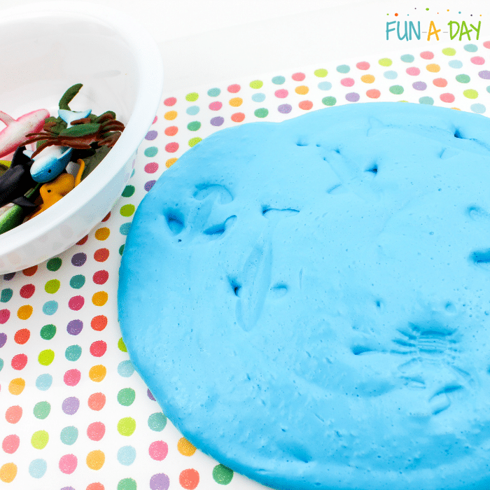 Blue ocean slime with imprints of sea creatures and a bowl of sea creature toys to the side.