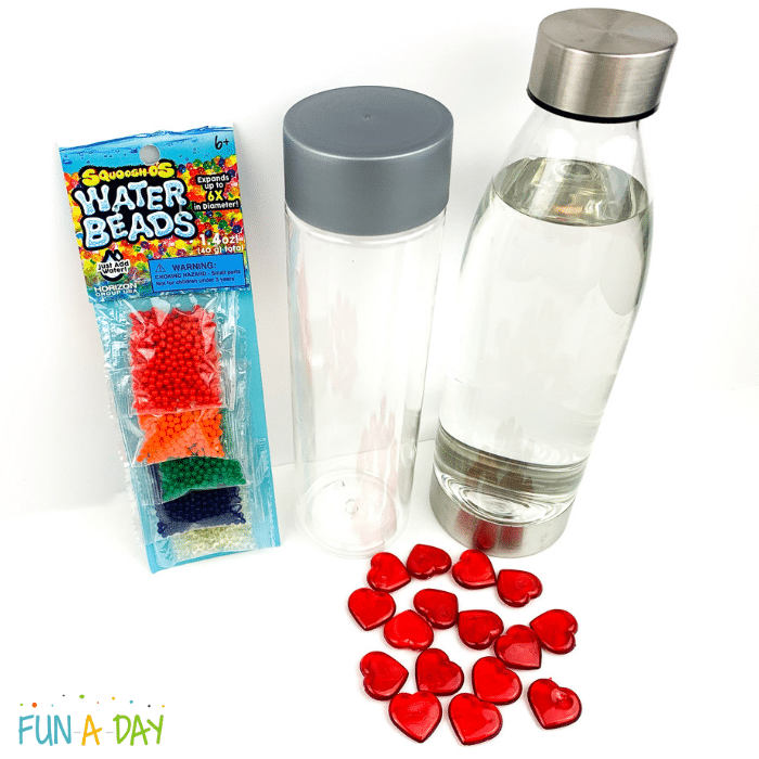 Materials used for the valentine sensory bottle which include water beads, plastic bottle, acrylic heart gems, and water.