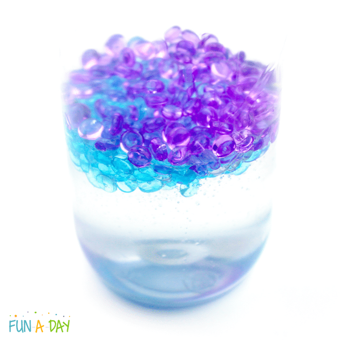 Clear glue with fish bowl beads floating on top of them in a sensory bottle.