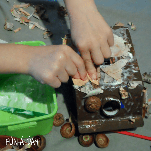 preschool child assembling a milk carton house