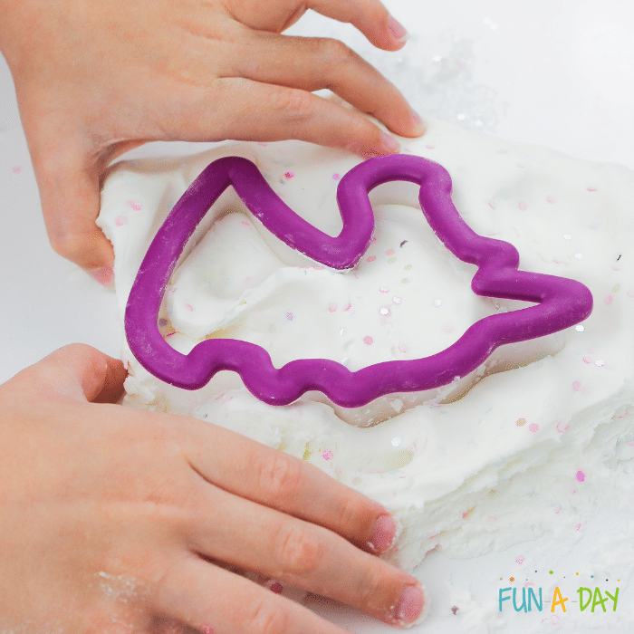 Preschooler's hands playing with unicorn play dough and unicorn cookie cutter.