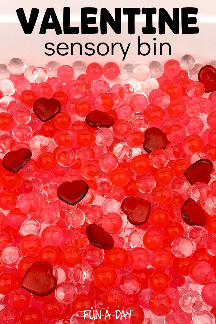 clear and red water beads in a bin with red acrylic hearts with text that reads valentine sensory bin