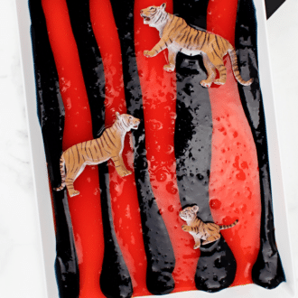 Orange and black striped tiger slime with toy tigers on top and text that reads tiger slime.
