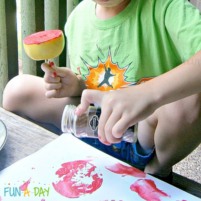 preschooler painting with an apple
