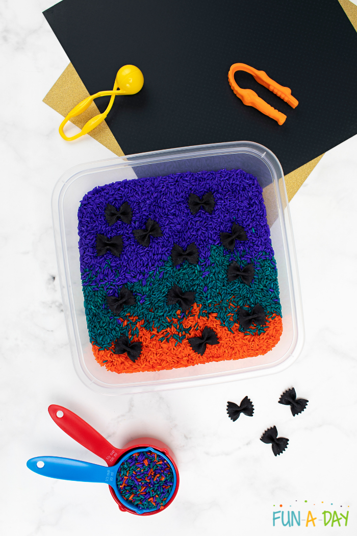 Colorful rice and black bat sensory bin for preschool