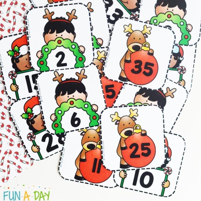A pile of cut advent calendar numbers with christmas illustrations and numbers on them - part of a preschool math activity