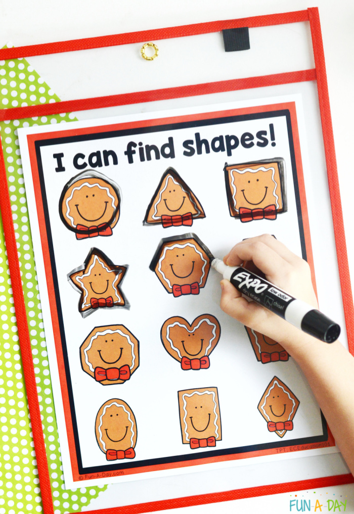gingerbread shapes on printable insode of a dry erase pocket with child's hand tracing the shapes with a dry erase marker
