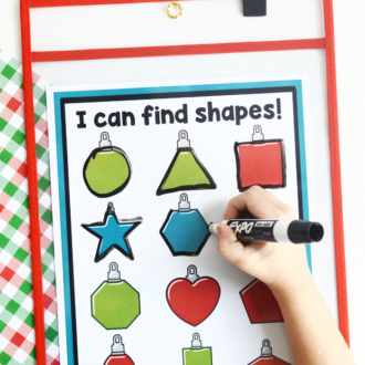 printed page of ornament shapes for preschool with child's hand tracing the shapes with a dry erase marker