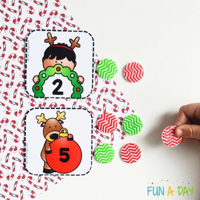2 printable calendar numbers on christmas wrapping paper with a child's hand using red and green buttons for a counting game
