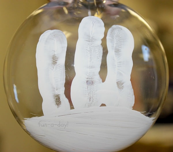 White paint handprint on Christmas ornament to make snowmen