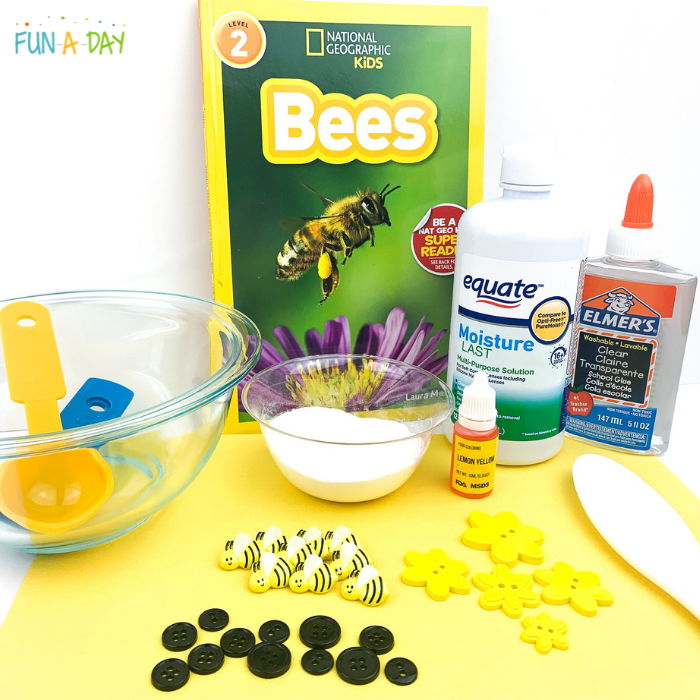 Materials needed for bee slime which include mixing bowl, measuring spoons, baking soda, contact lens solution, Elmer's clear glue, yellow food coloring, bee-themed buttons, and a National Geographic Bees book.
