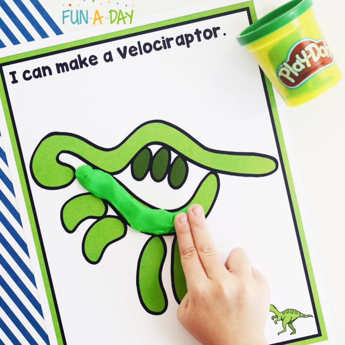 Person using play dough to make the shape of a velociraptor on the free printable mat.