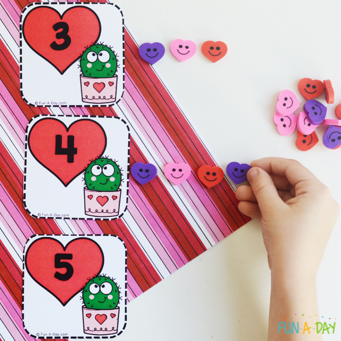 valentine calendar number cards with a child's hand using heart erasers