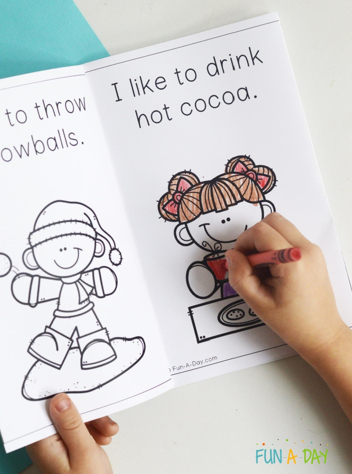 young child's hand coloring in a winter printable book with crayon