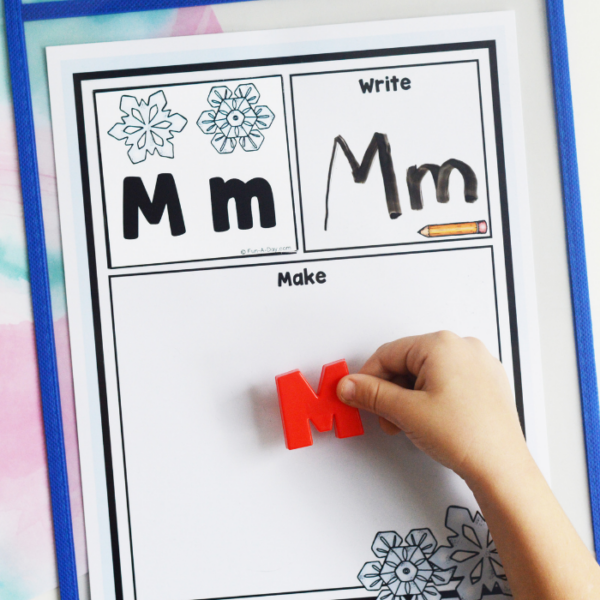 preschooler adding letter M to a winter read write build mat