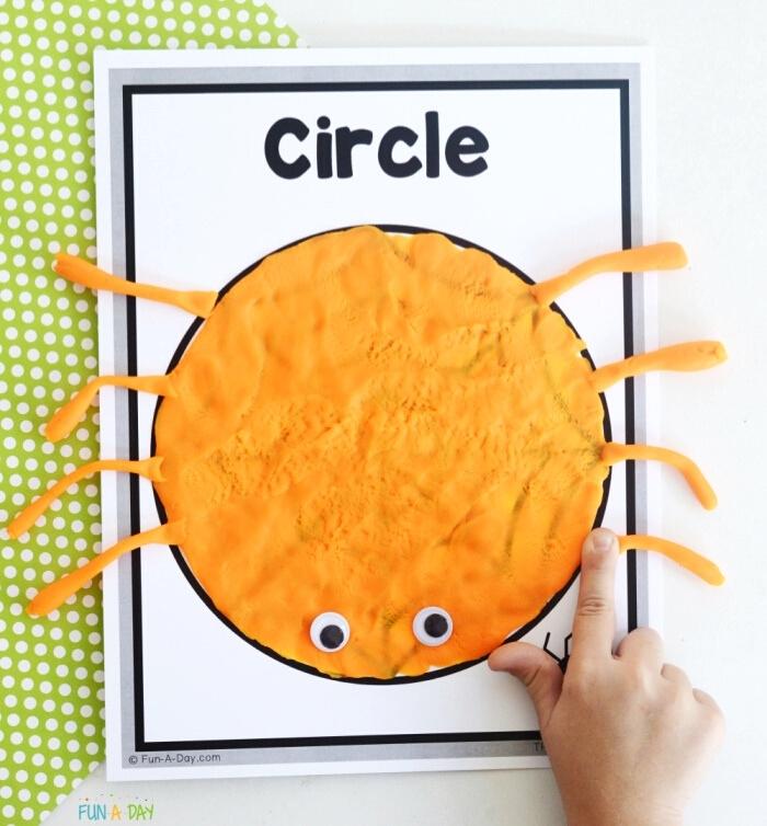 printable spider shape mat for preschool with child's hand spreading play dough on it