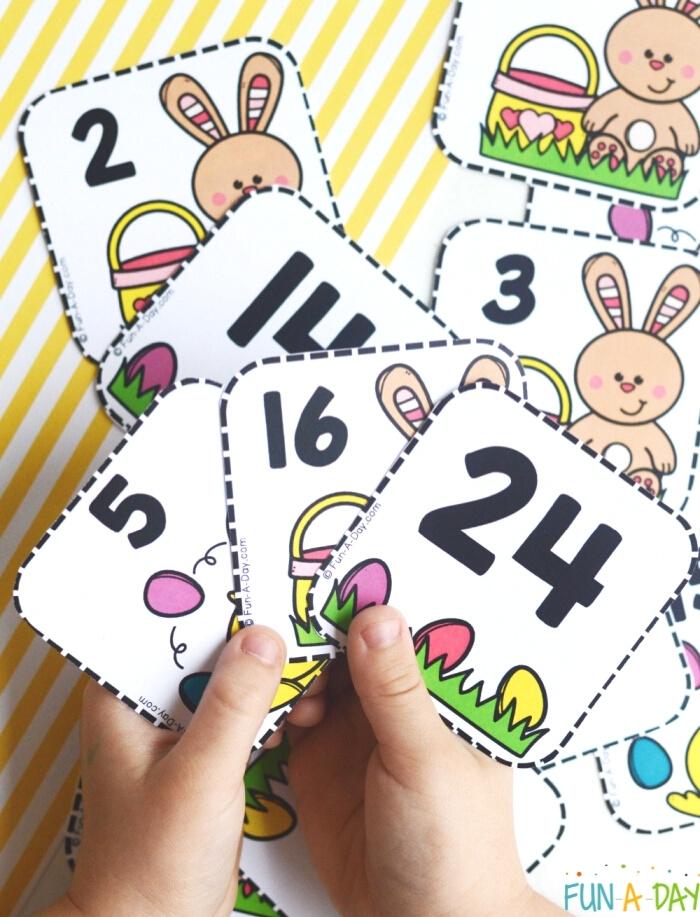3 Easter calendar number cards with Easter images - child's hand holding them