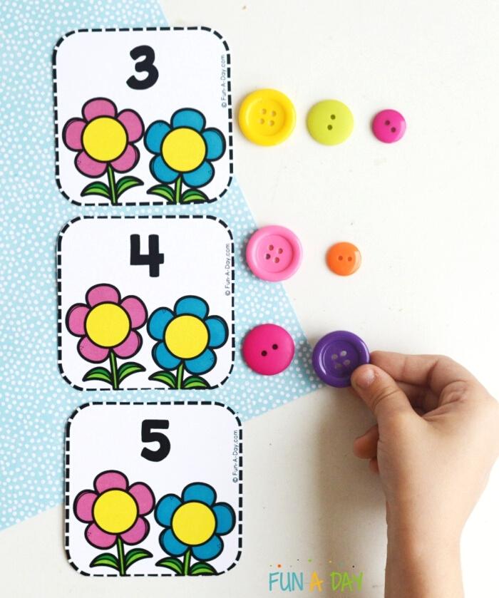 spring calendar number printables for preschoolers - flowers with numbers and child's hand next to them with colorful buttons