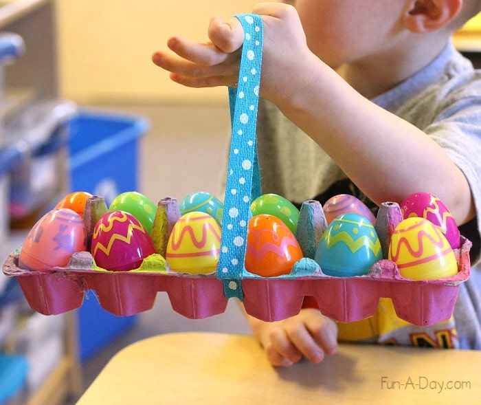 Preschooler holding a recycled easter basket made from egg carton, with plastic eggs inside