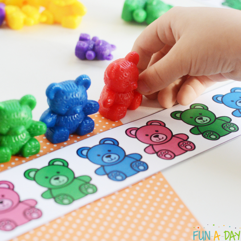 Child's hand making patterns with counting bears and free printable bear pattern strips.
