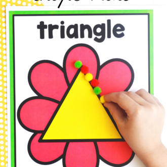 child's hand placing pom poms on a triangle flower shape mat