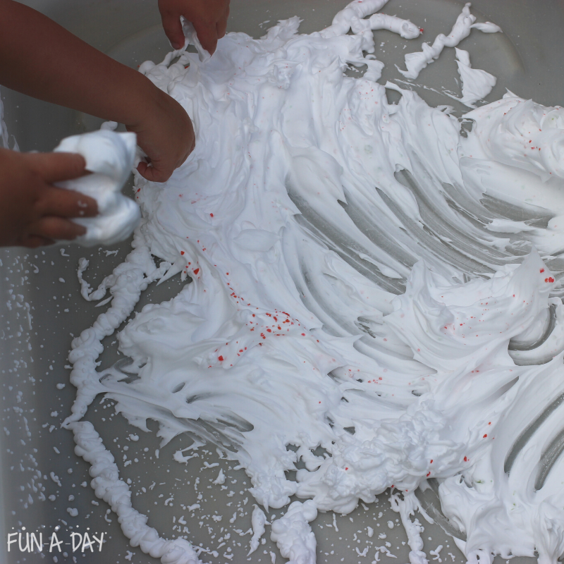 Preschoolers' hands in bin of shaving cream with pop rocks