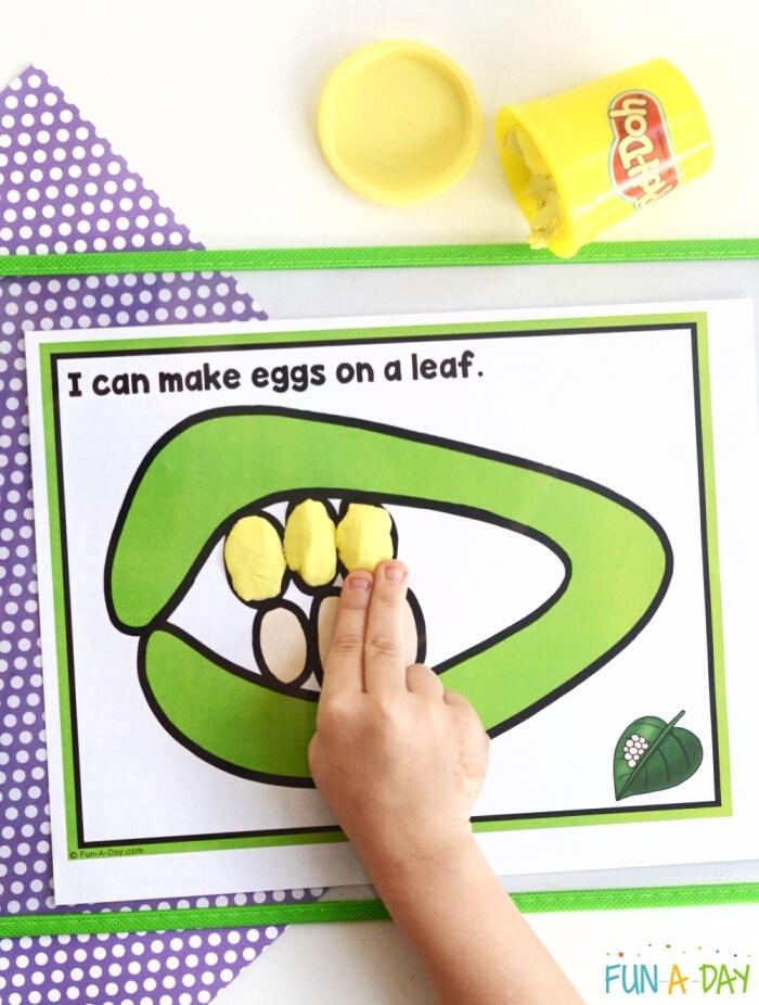 Child pressing yellow play dough into a butterfly playdough mat