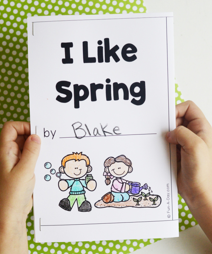 child's hands holding up colored-in I Like Spring printable book