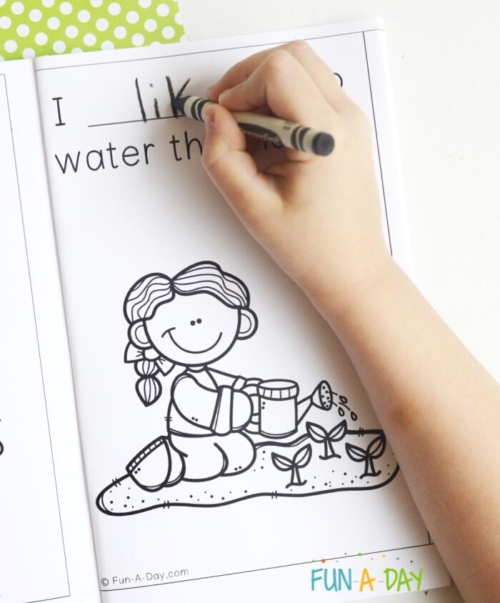 child's hand writing the word, 'like' with crayon in a printable preschool book about spring