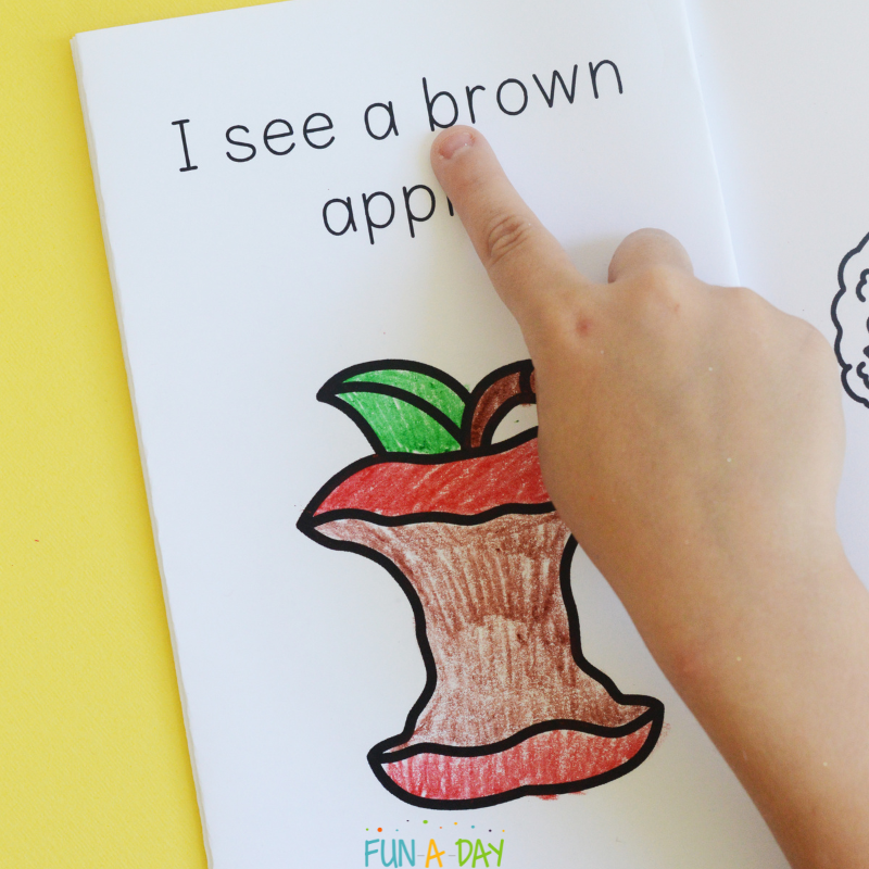 Preschooler pointing to words in a printable apple book