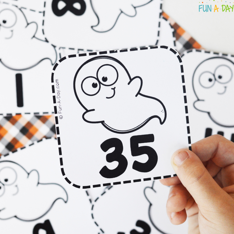 child's hand holding up ghost printable number 35
