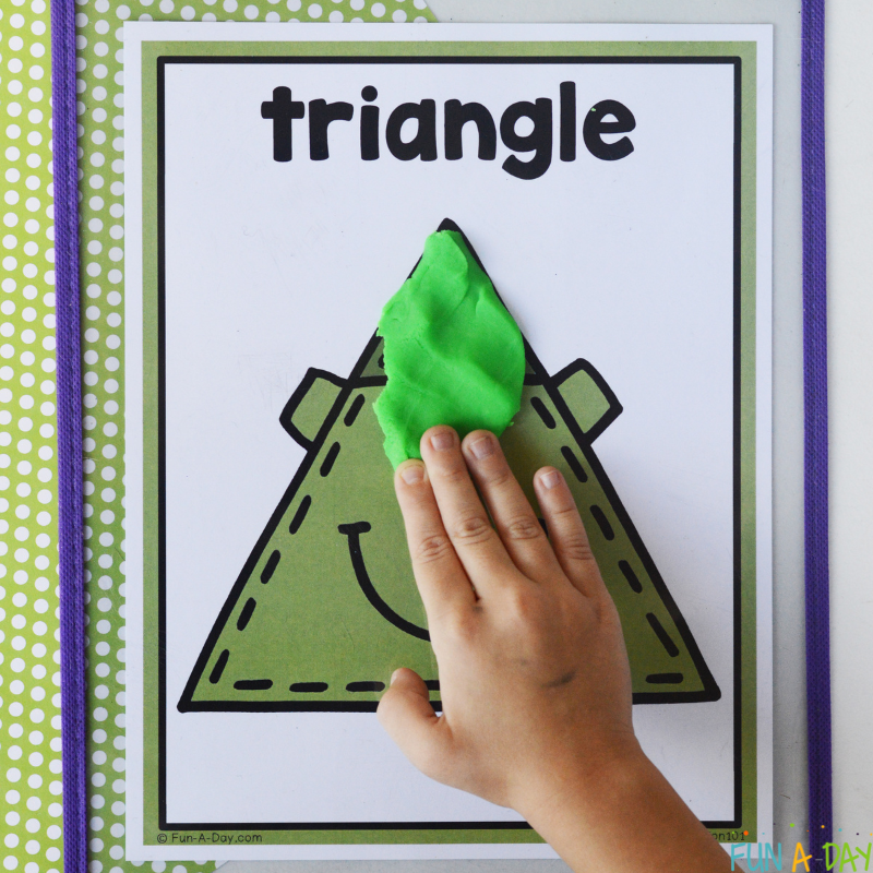 preschooler using green play dough on monster shape mat