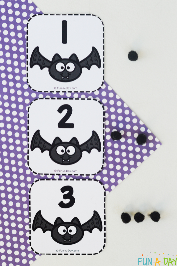 3 bat number cards with corresponding number of black pompoms next to each