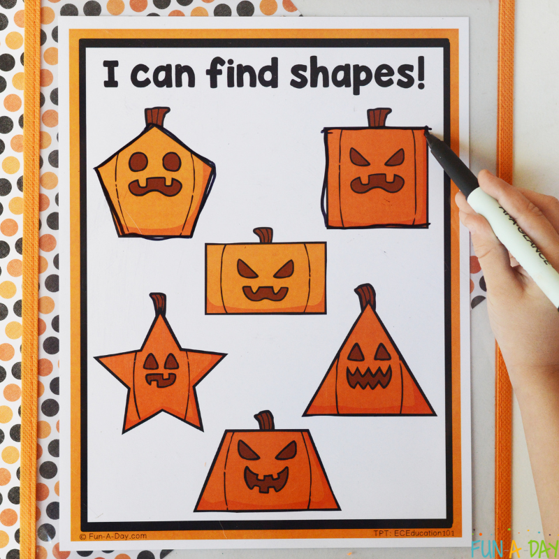 child using dry erase marker to trace over jack-o-lantern shapes on printable page