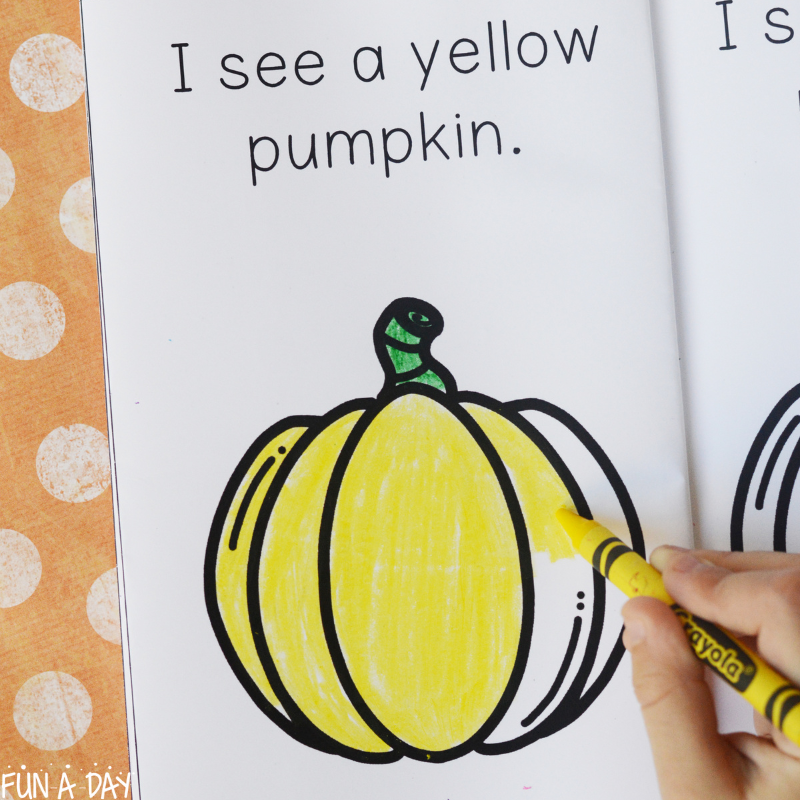child coloring in printable book page that reads I see a yellow pumpkin