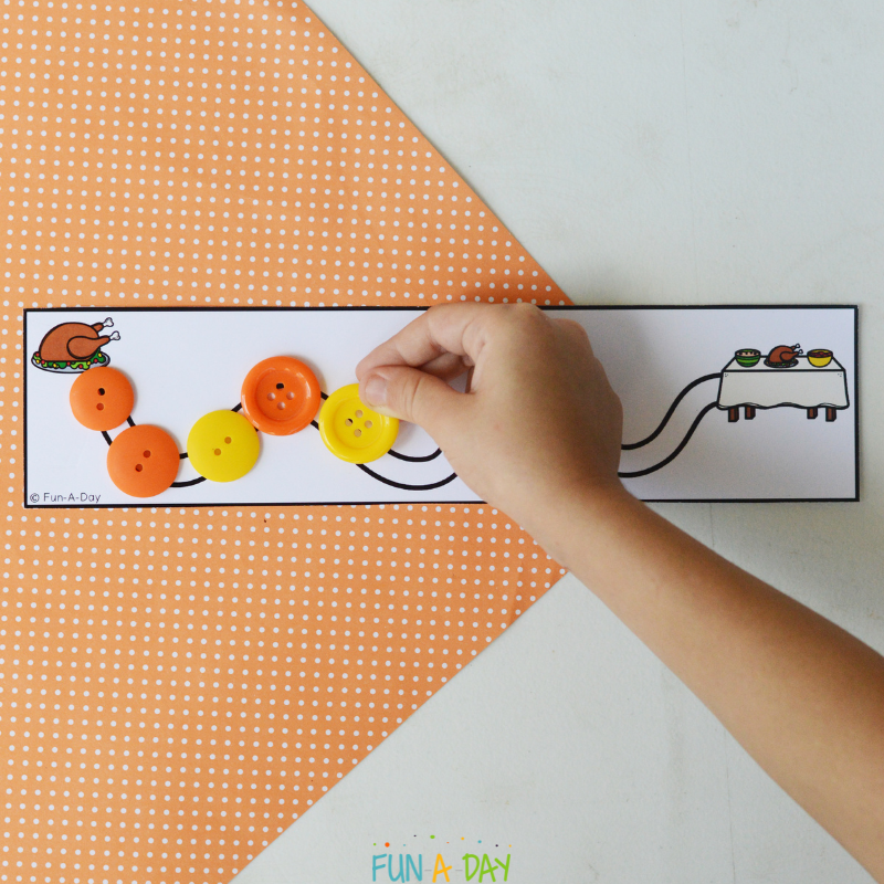 preschooler using buttons to trace over line on thanksgiving tracing printable