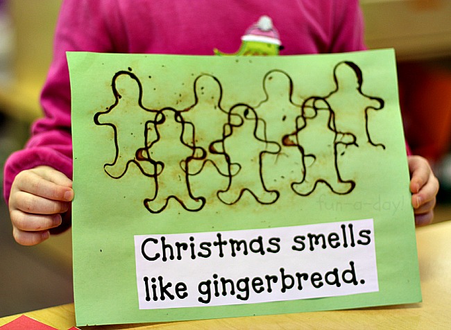 child holding a page from her christmas senses book that reads christmas smells like gingerbread