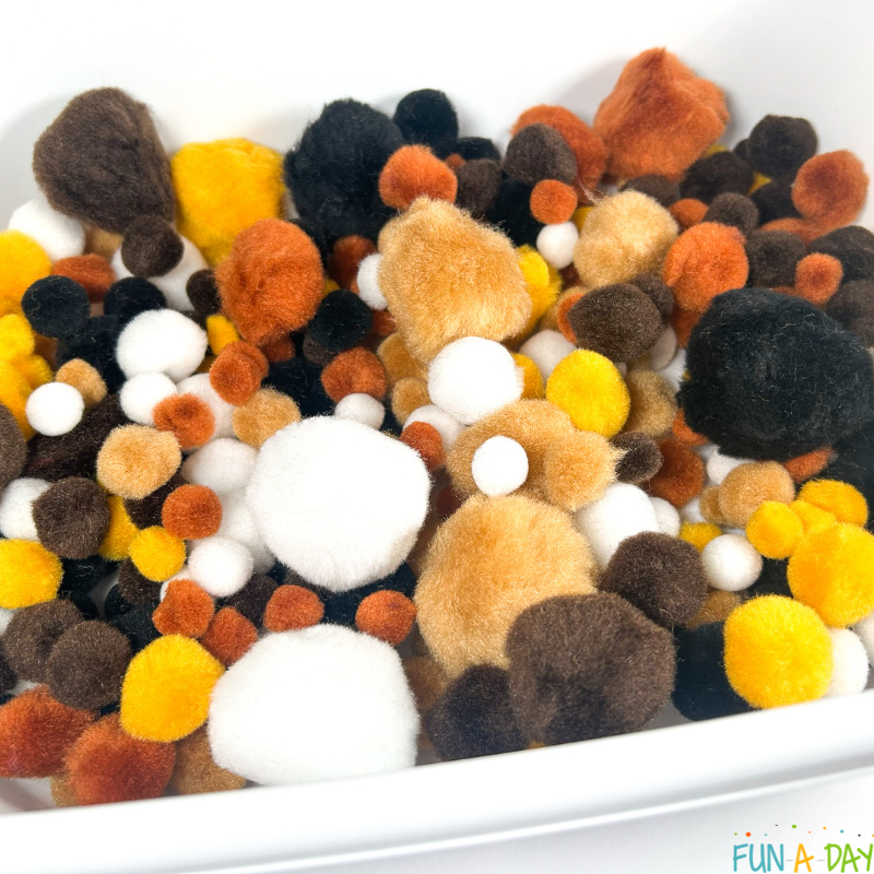 pompom messy play in shades of brown, black, and white