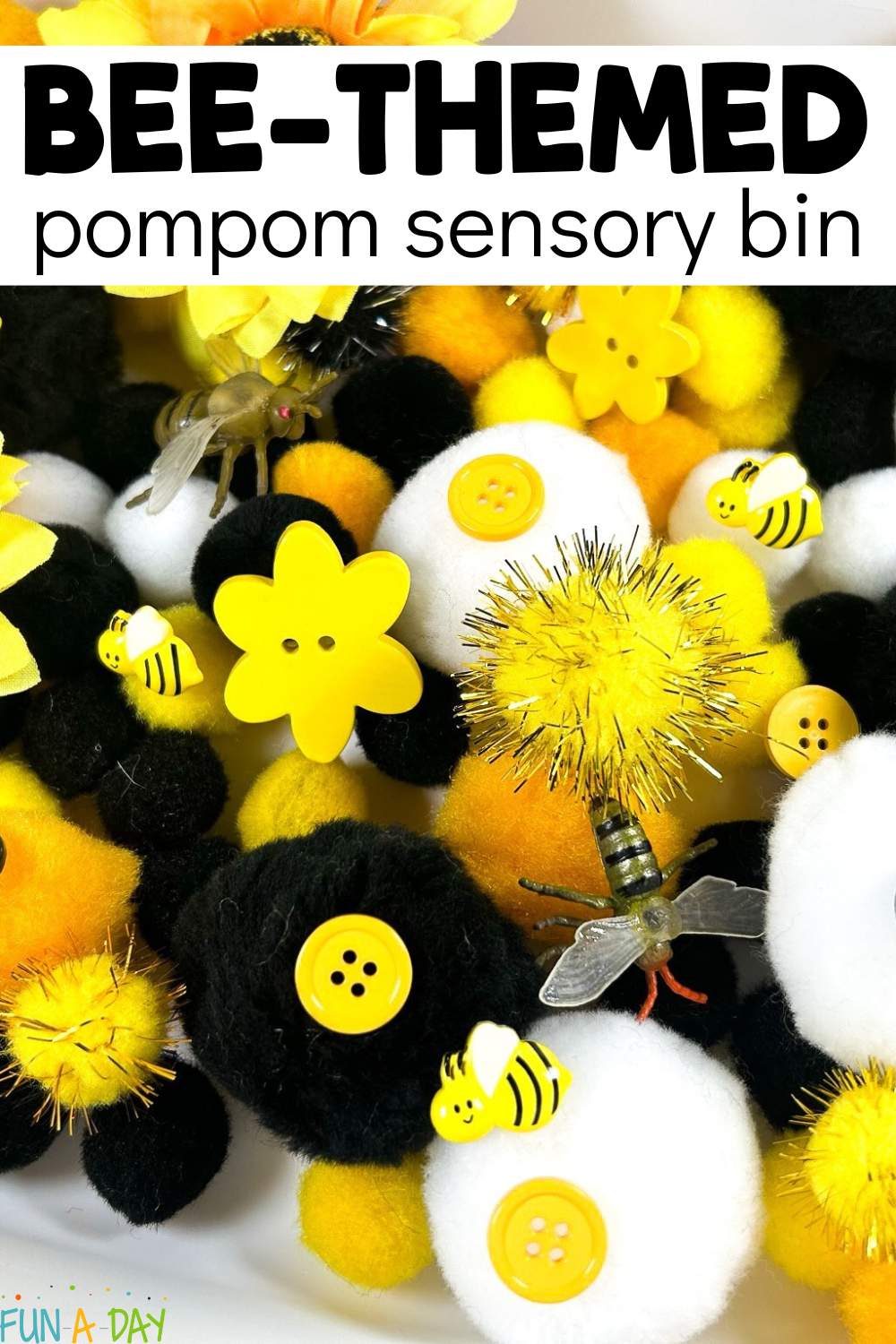 Close up of yellow, black, and white pompoms, buttons, and toy bees with text that reads bee-themed pompom sensory bin