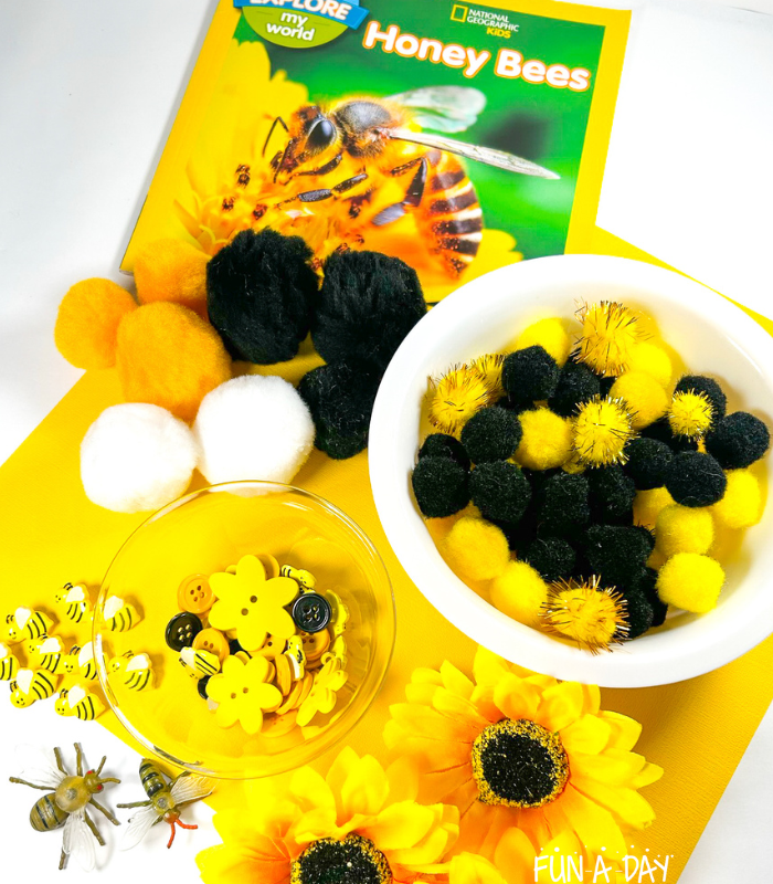 pompoms, buttons, fake flowers, bee toys, and bee book to make a sensory bin
