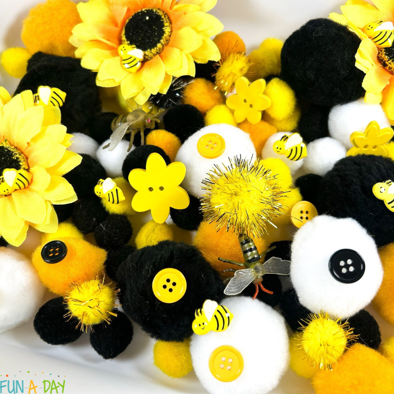 yellow, black, and white bee pompom sensory bin
