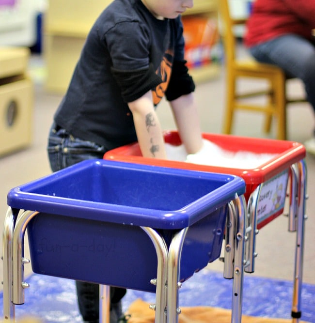 preschool child with hands in spring soapy sensory bin