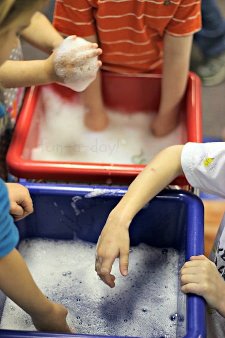 preschoolers using their hands to play with scented soapy water bin