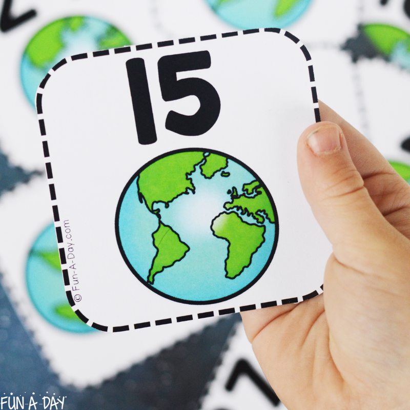 child's hand hlding up earth number card 15