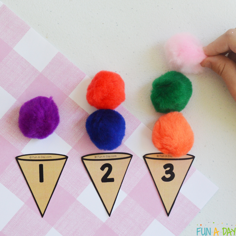child placing appropriate number of pompoms on printable ice cream cone numbers
