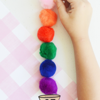Child adding colorful pompoms to a numbered triangle with text that reads ice cream math